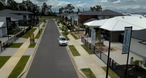 Image of North Harbour display village showcasing display homes in Burpengary East, Brisbane. There are houses lining a pleasant street with clouds in the background.
